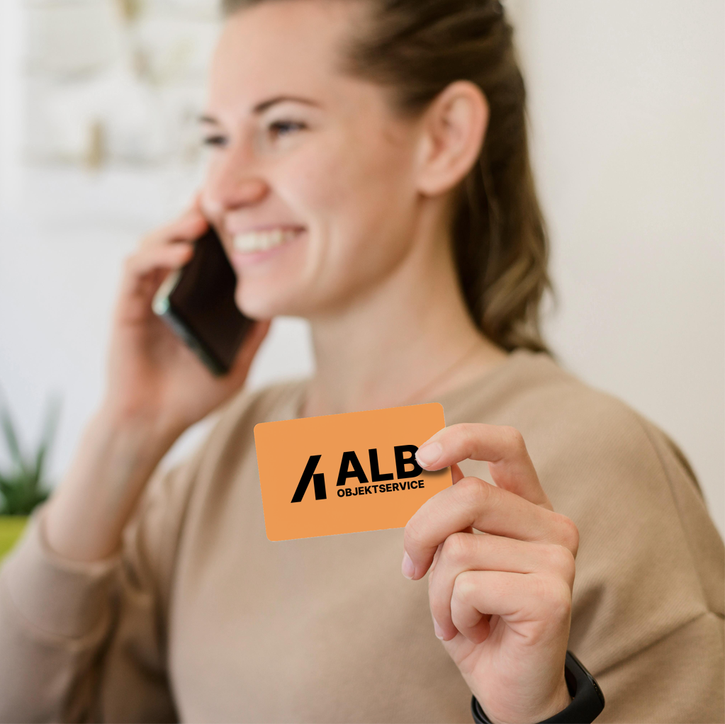 Frau hält eine ALB Objektservice Karte in der Hand und telefoniert – Symbol für Kundenservice und Erreichbarkeit